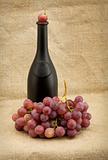 Dark bottle and red grapes bunch