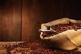 Burlap sack of coffee beans against dark wood