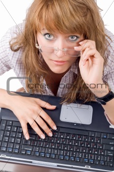 The tired young woman in glasses sits with the laptop. Isolated