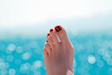 Female foot over blue ocean on sunny summer day