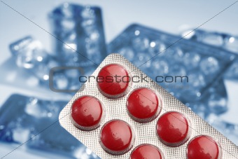 Red medicine pills over an empty blisters background
