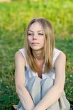 A beautiful young woman sitting in the grass