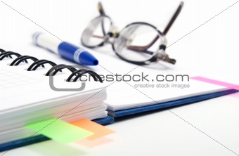 pen and glasses on notebook with bookmarks 