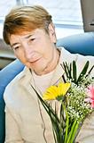 Sad elderly woman with flowers