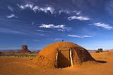 Hogan - the traditional Navajo red clay earth house, with backdrop of famous table mountains of the Navajo National monument on the background