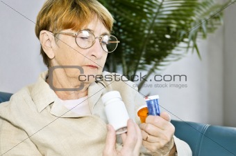Elderly woman reading pill bottles