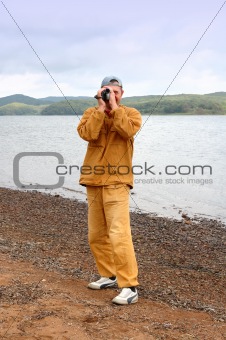 Cameraman on sea shingle beach.