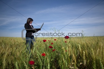 young businesswoman with laptop on poppie field