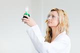Woman in lapcoat looking at chemicals
