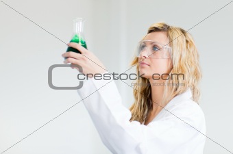 Woman in lapcoat looking at chemicals