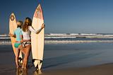 Two girls standing with surfboards