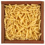 uncooked fusilli pasta in wooden box