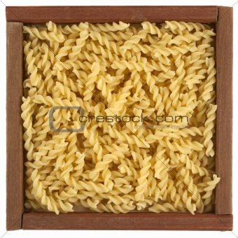 uncooked fusilli pasta in wooden box