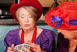 Ladies wearing red hats playing cards
