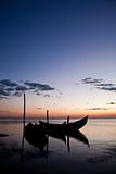 Photo of boats silhouettes by the shore, at sunset.