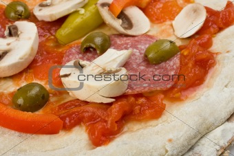 unbaked pizza prepared to bake on a wooden board