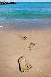 Footprints leading into a blue ocean