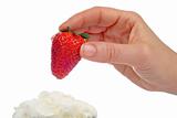 Woman hand strawberry over cream