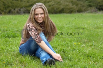 cheerful girl sitting on the green grass.