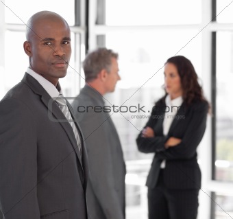 Serious business leader looking at camera in front of team 