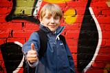 Kid standing in front of a graffiti wall