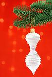 White Finial Shaped Cristmas Ornament Over Red Background On Nob