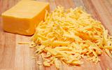 Grated cheddar cheese on wooden board