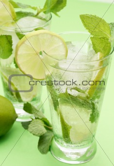 Two mojito cocktails on green background