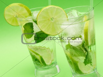 Two mojito cocktails on green background