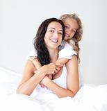 Mother and daugther embracing on bed
