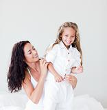 Mother and daughter on bed smiling at camera