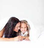 Mother and daughter on bed smiling at camera