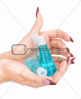 Beautiful wet hands holding bottles with shampoo