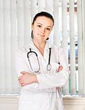 Portrait of female doctor standing in front of office window