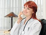 Young female doctor calling on phone, smiling.