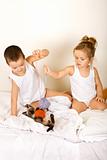 Kids playing with their kitten on the bed