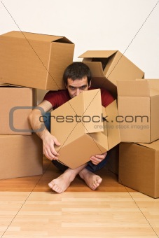 Man under cardboard boxes on the floor - moving concept