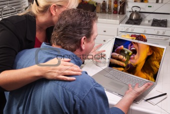 Couple In Kitchen Using Laptop with Singing Woman on the Screen.
