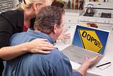 Couple In Kitchen Using Laptop with Yellow Oops Road Sign on the Screen.