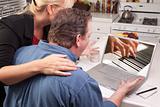 Couple In Kitchen Using Laptop with Piano Performer on the Screen.