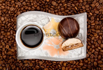 Coffee cup with sweets on beans background 