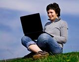 Young casual woman working on laptop outdoors