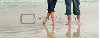 Couple walking on the beach showing legs only