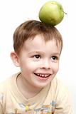 The cheerful child with a green apple on a head