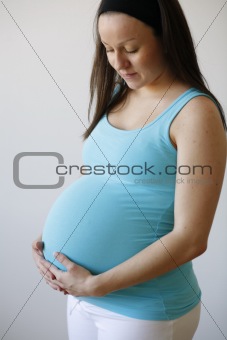 Young thoughtful pregnant woman holding her tummy.