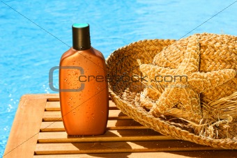 Tanning lotion with sun hat by the pool