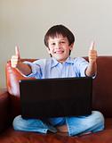 Child playing with his laptop with thumbs up