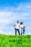 Happy young family on green grass over sky