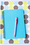 Brightly colored notebook, folder and pen.