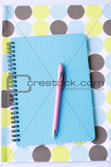 Brightly colored notebook, folder and pen.
